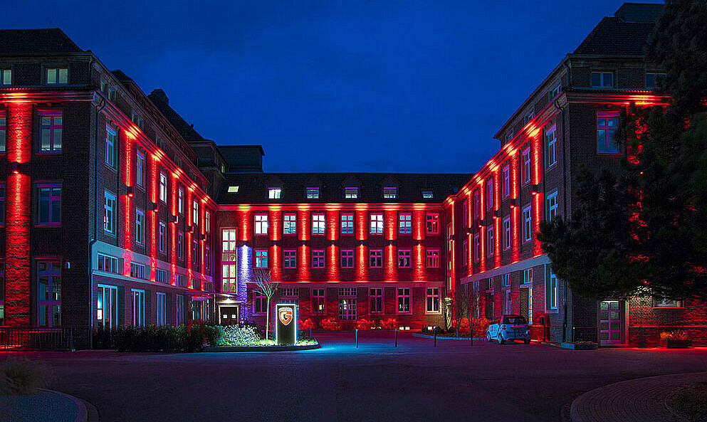Der ehemalige Konsumverein Wohlfahrt bildet heute den lebendigen G DATA Campus. Abbildung des beleuchteten G DATA Campus